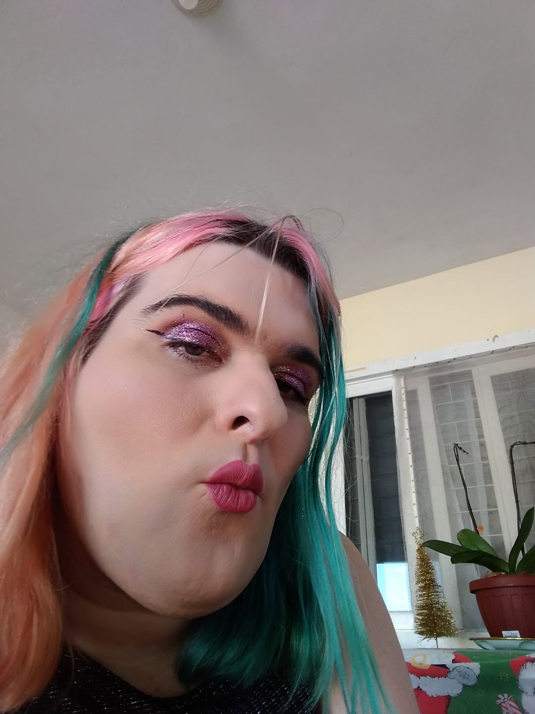 Selfie divertida de Paloma mandando beijo, cabelo metade rosa pêssego e metade verde-água