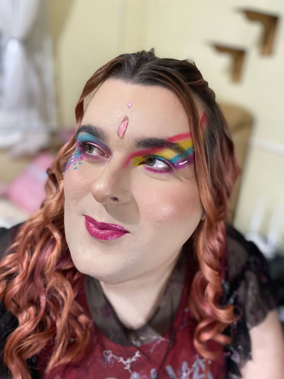 Paloma com maquiagem arco-íris nos olhos e um cristal rosa na testa, olhar sonhador para o alto